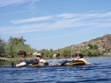 Wild Horses provide a picturesque background for this photo of PC Singles Club members Jackie Havranek and Rosemary Vana during one of the more peaceful moments of their recent tubing trip on the Salt River.