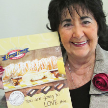 Carol Phillips of our Friendship Committee holds a small poster for Butter Braids.