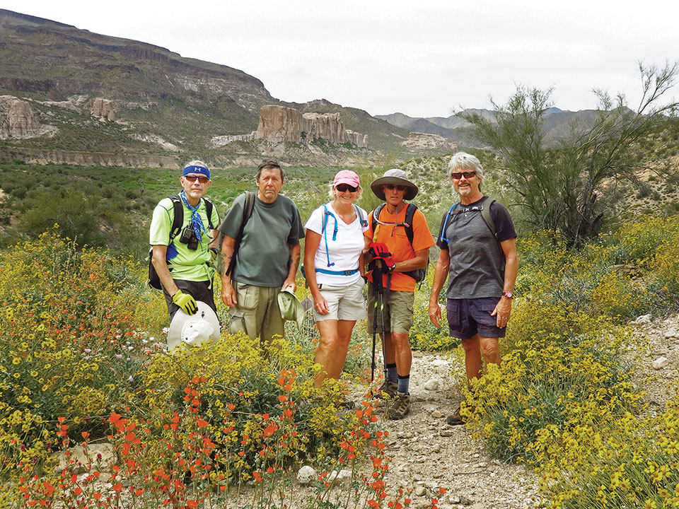 Left to right: Lynn Warren (photographer), Len “London” Jeffery, Julie Walmsley, Mark Frumkin and Gary Bray pose in brittlebush and globe mallow with Shiprock in the background.