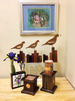 Well, Hello There is the title of the featured painting; also highlighted are a carving of three quail in a row running across a picket fence, a wooden pencil box with a ceramic tile focal piece and walnut candle holders with hammered copper inserts.