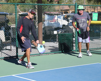 Steve Cain and Bob Chester demonstrate a serving technique called stacking, common with left-handed players; Photo by Dannie Cortez.