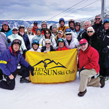 PC skiers Lynn Warren, Lew and Rose Geller together with other members of Valley of the Sun Ski Club pausing for a group photo with the Village Lift at Snowmass (Aspen) in the background; photo by Mary Ann Vangelisti.