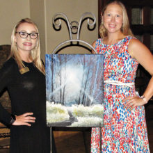 Assistant Event Coordinator Sabrina Minney (left) and Event Coordinator Crystal Thomas pose with the painting created for the July Paint and Wine event.
