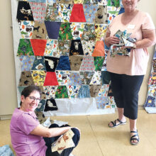 Nadine Eder and Cathy Davis arranging precut blocks for their community service quilt that features animals.