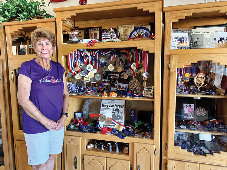 Mary Lou Furaus at home with her racquetball and pickleball trophies and medals