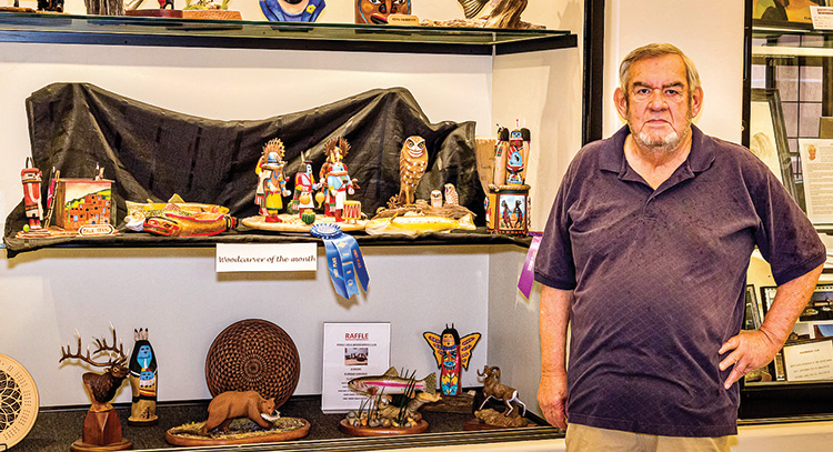 Dale with several of his carvings on the middle shelf of the display window in the Creative Arts Center.