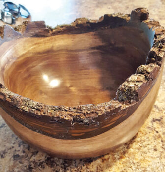 Chuck Schuldt, also known as WoodChuck by his fellow carvers, “turned” a bowl. Chuck commented, “It is called a "live edge bowl" because I’ve finished the bowl with the bark on it. I had to make the walls a little thicker than I would have normally to keep the bark intact. The bowl is nine inches outside. Please note that I was also able to retain some moss on the edge/bark. The bowl is from black walnut that a friend of mine gave me. It was a little green and was relatively easy to turn. I turned the bowl from the side of the piece of wood, giving it the "dished" look from the side view.”