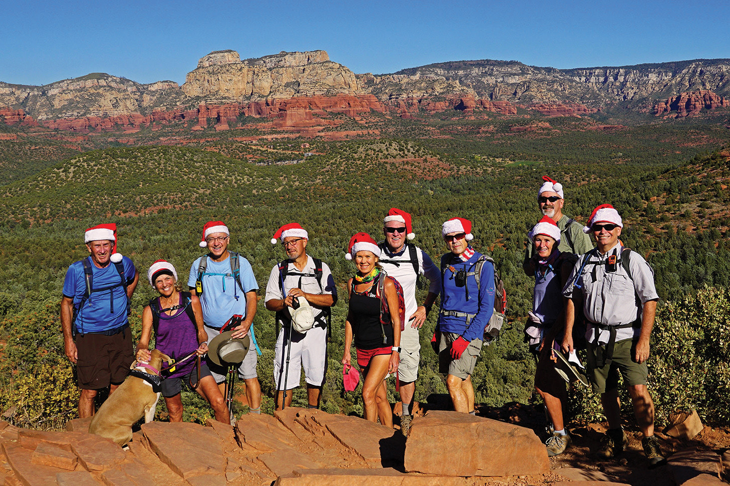 Left to right: Clare Bangs, Annie (guest dog), Marilyn Reynolds, Wayne Wills, Ron Hoffman, Kris Raczkiewicz, Mike Trapp, Lynn Warren (photographer), Eileen and Leon Mosse, and Neal Wring pausing on the Devil’s Bridge trail with beautiful Sedona scenery in the background.