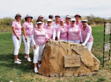 The Gimme Girls Golf Group gathered in front of a rock placed in memory of the founder of the Los Caballeros Golf Club in Wickenburg. Front row (left to right): Sharon Johnson, Suzan Simons, Kathy Carney, Barb Chilton, and Sue White; Back row: Mary Barry, Judy Layton, Maria Murray, Carol Mathias, Cheryl Skummer, Lynn Grice, and Jayne Dinan